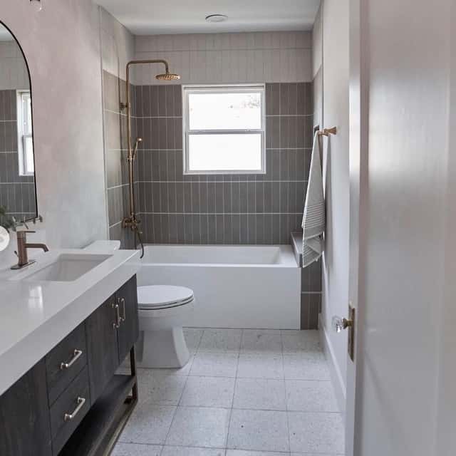 Remodeled bathroom with a dark vanity and a tiled tub-shower — Sky Property INC, Baltimore, MD