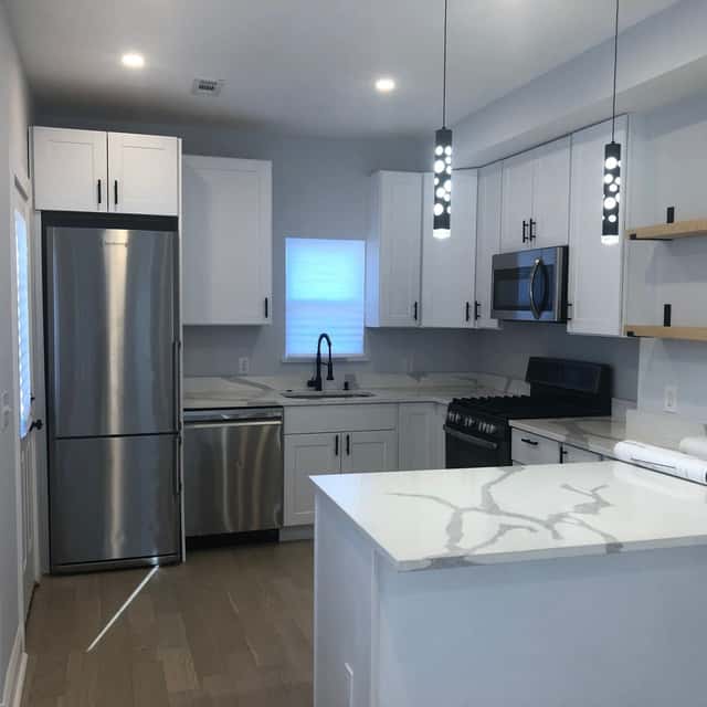 Finished white kitchen with a quartz island and stainless appliances — Sky Property INC, Baltimore, MD