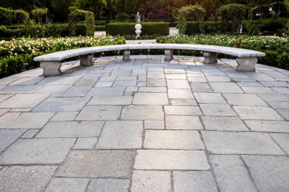 Curved paver patio with a seating wall and manicured landscaping