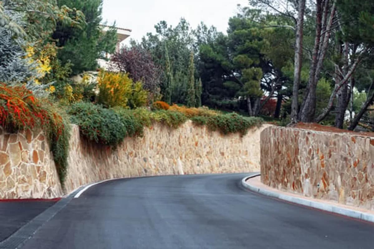 Finished stone retaining wall holding a landscaped grade change